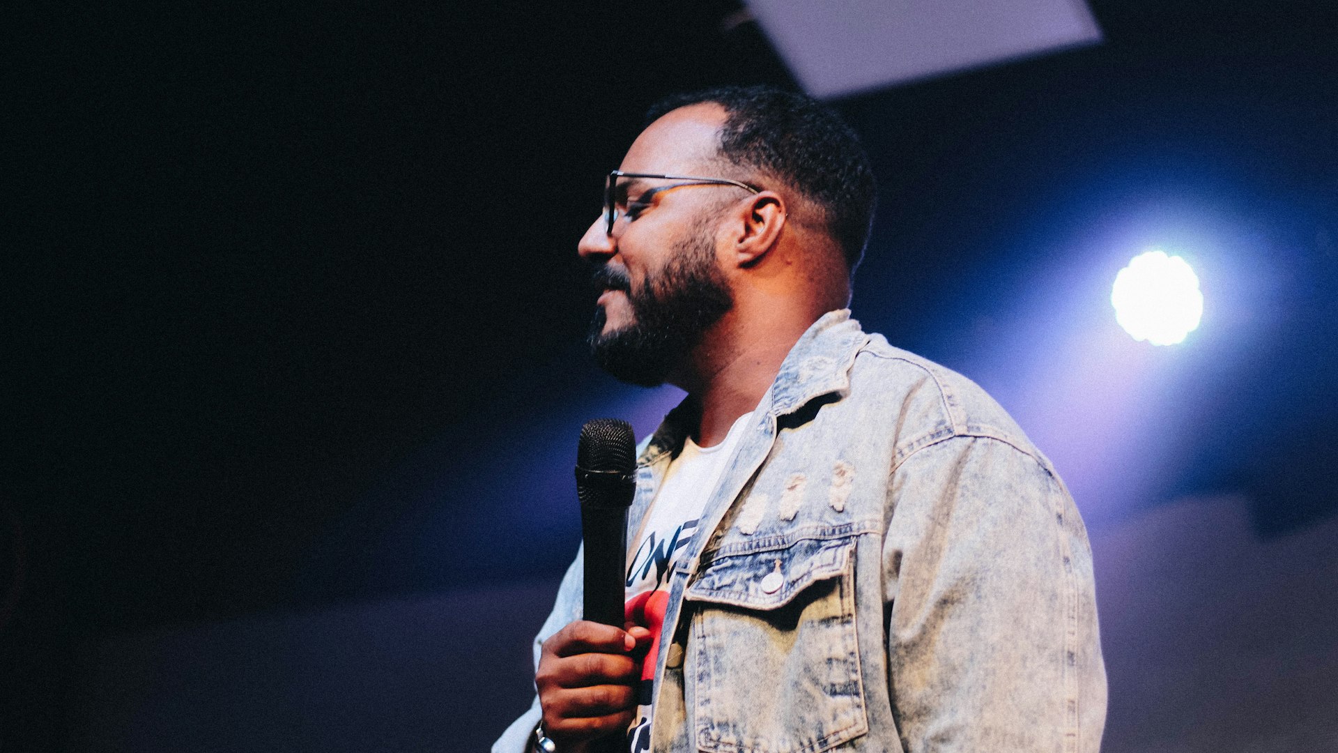 Man holding a microphone while speaking on a church stage