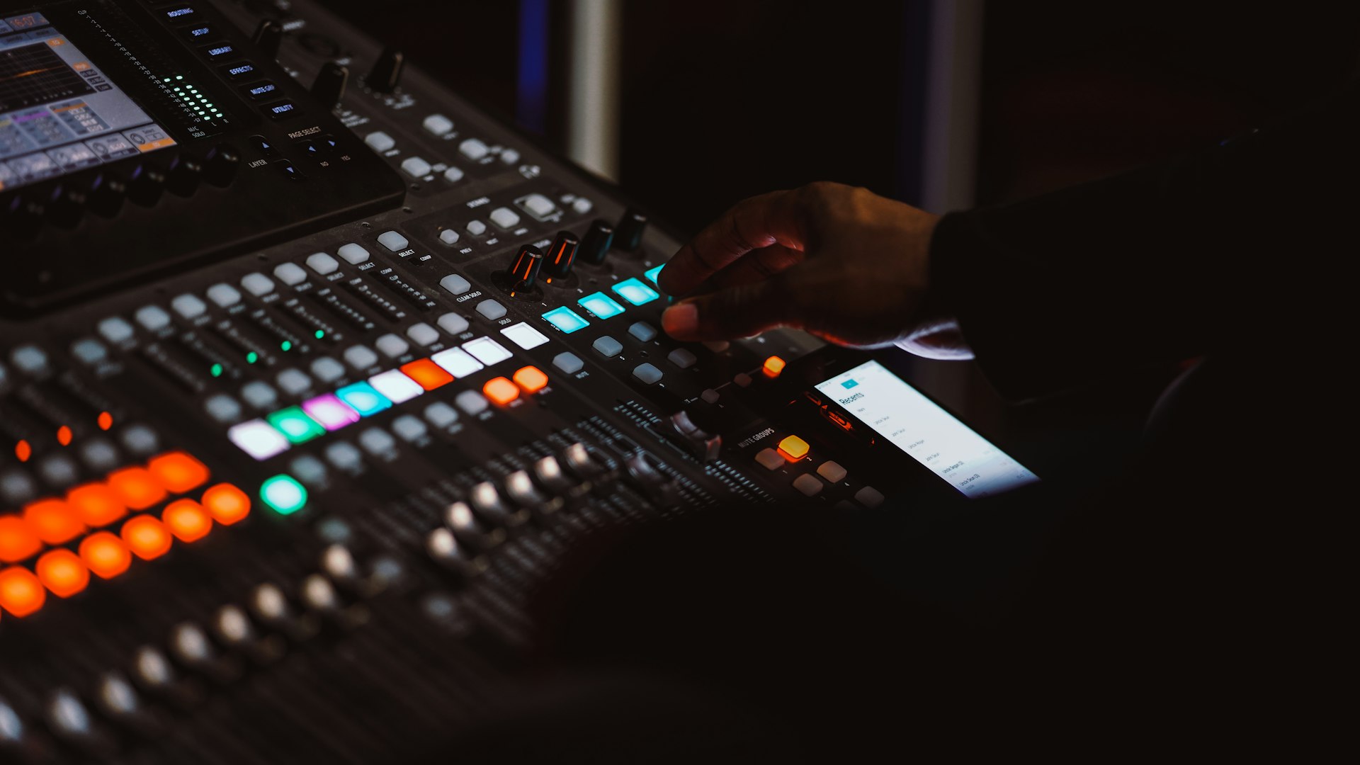 Hands adjusting a church audio mixing console